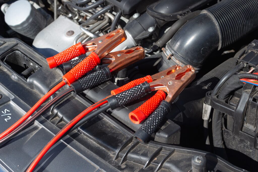 two battery jumper cables attached to a car battery